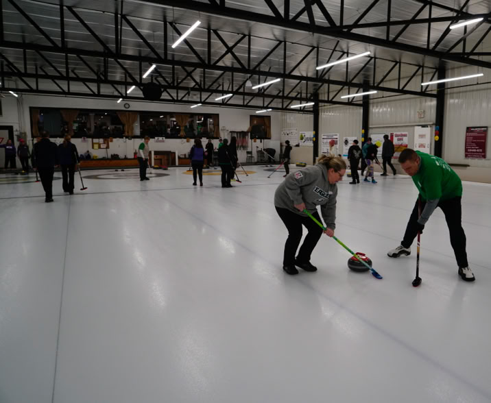 Two team members sweeping in front of rock at 2024 Curl For A Cause.