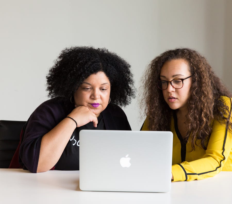 Two women looking at a Macbook screen